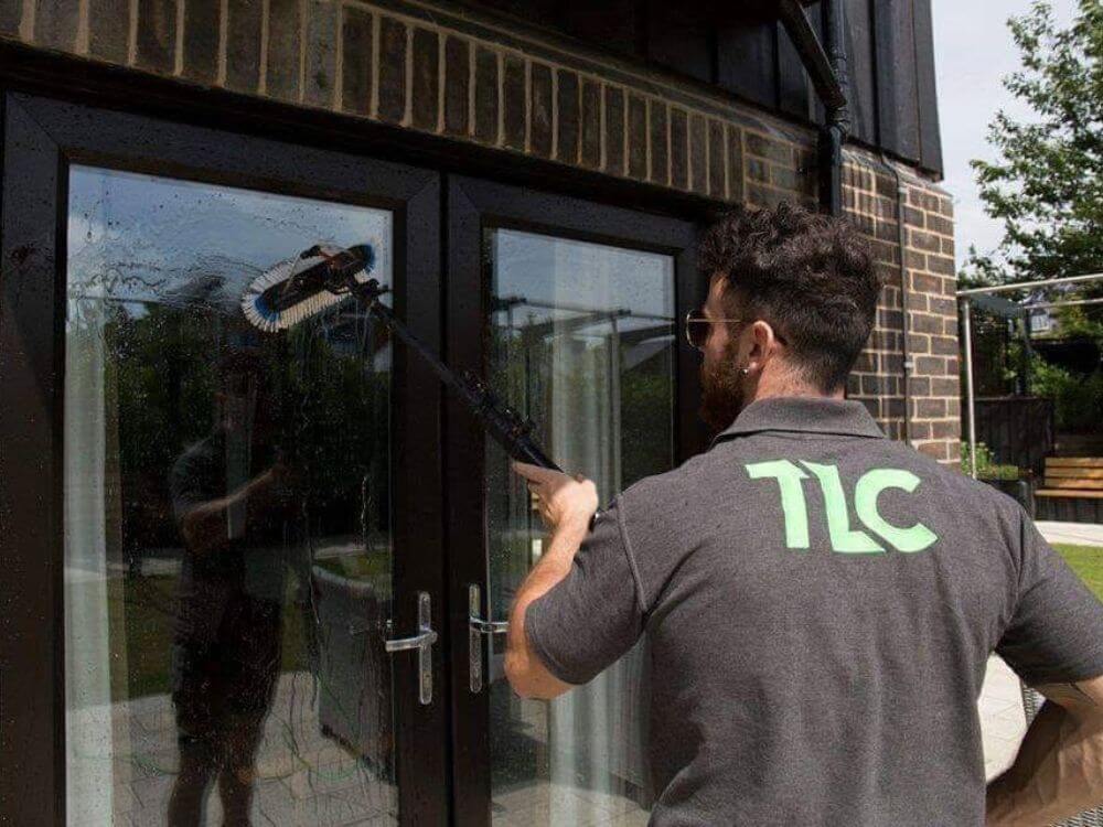 TLC Window Cleaning technician professionally cleaning glass doors at a residential property.